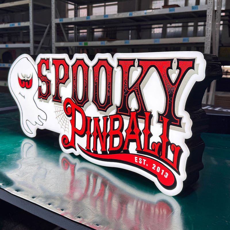 Factory batch production of custom LED acrylic signs on workbench including American Pinball, Williams, Barrels of Fun, and Spooky Pinball